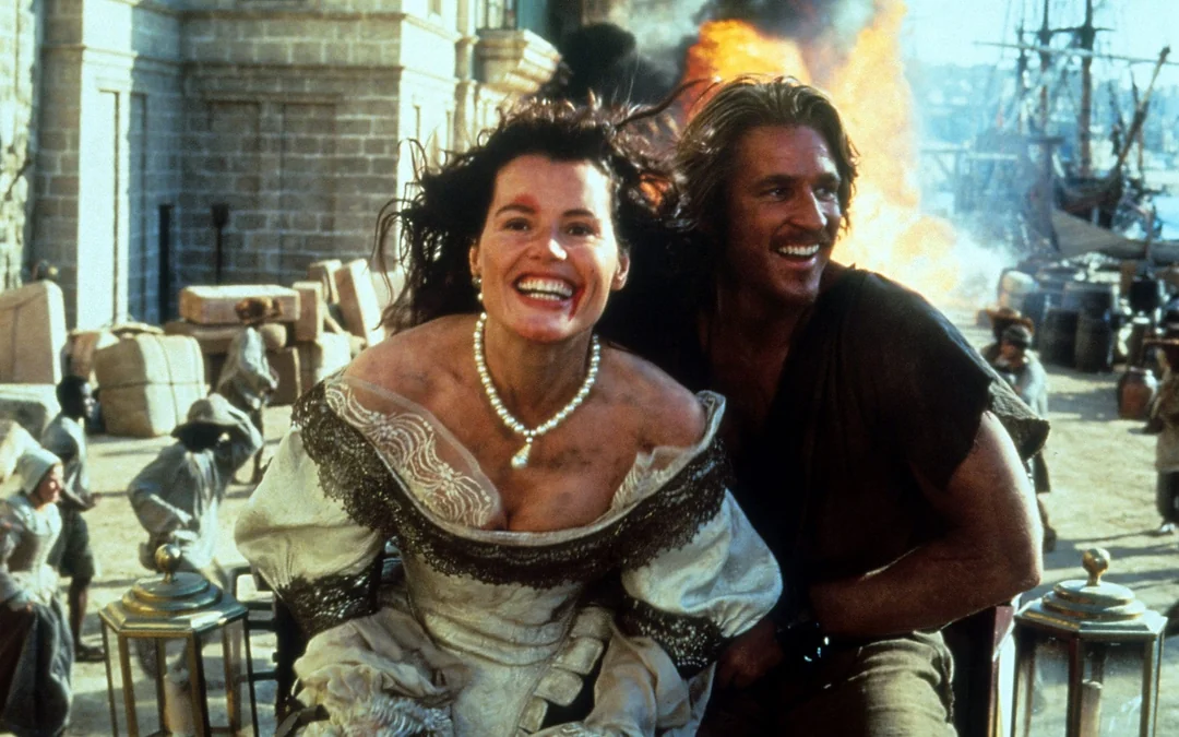 A woman in a white, old-fashioned dress and a man in rugged clothes smile joyfully as they ride away from a large explosion, with ships and people in the background of a historical port town.