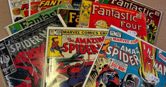 A collection of vintage Marvel comic books, including "The Amazing Spider-Man" and "Fantastic Four," some in plastic sleeves, spread out on a flat surface. Price stickers are visible on the covers.
