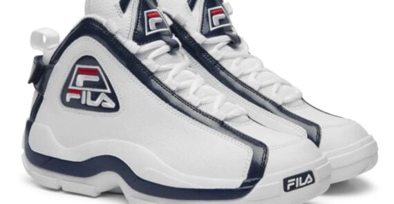 A pair of white FILA athletic sneakers with navy blue accents, featuring the FILA logo on the side and tongue, displayed against a plain white background.