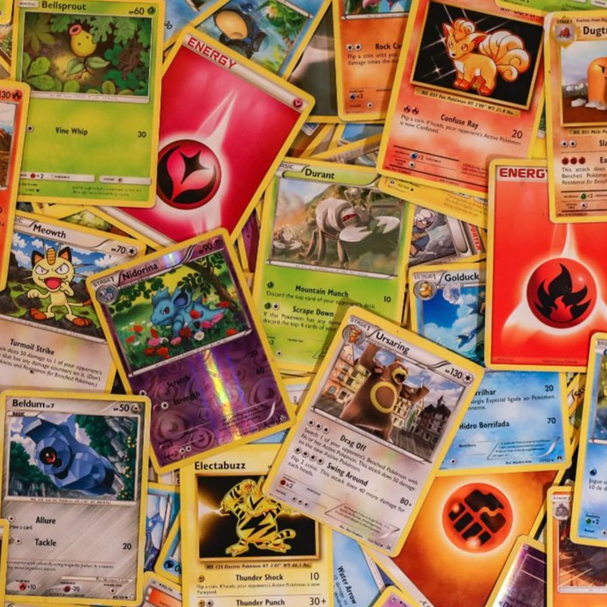 A colorful assortment of Pokémon trading cards scattered over each other, featuring various Pokémon characters, energy cards, and different card designs and colors.