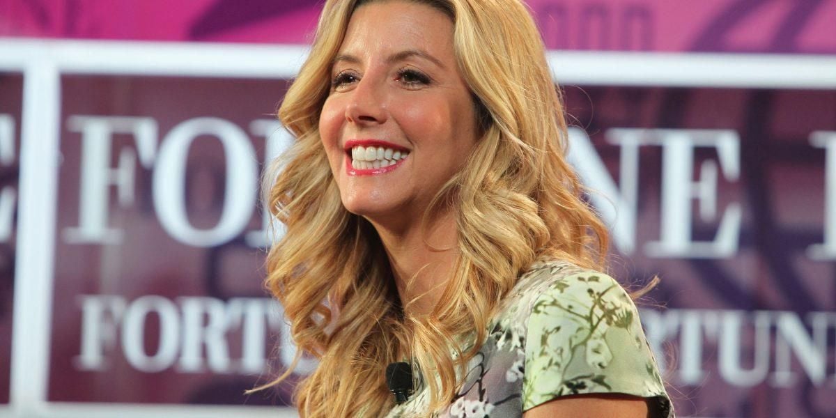 A woman with long blonde hair and a floral top smiles while sitting in front of a blurred background with the word "FORTUNE" displayed multiple times.