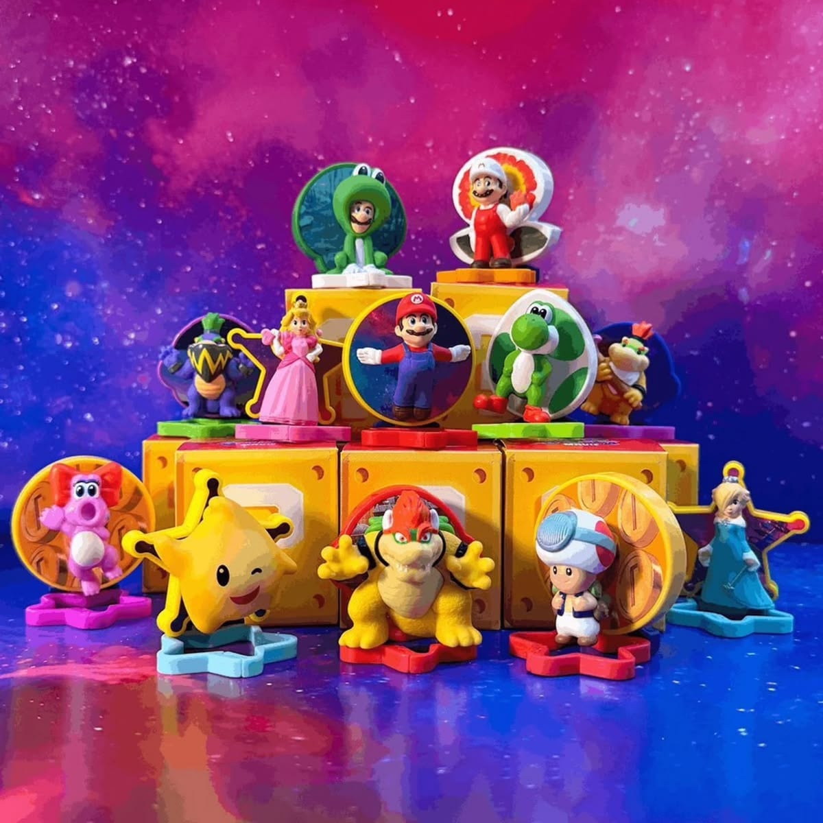 Colorful Super Mario toy figures, including Mario, Luigi, Princess Peach, Yoshi, Toad, and others, are arranged on yellow blocks against a vibrant pink and purple space-themed background.