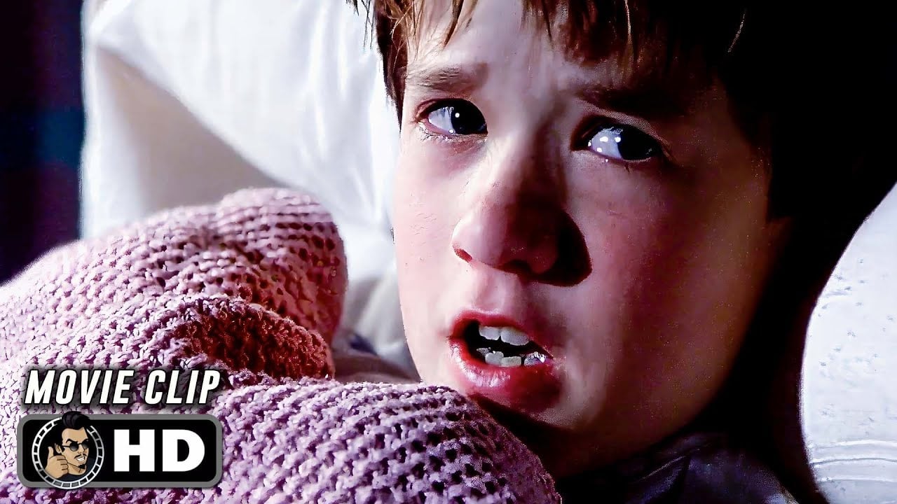 A young boy with a fearful expression clutches a pink blanket while lying in bed. The image has "MOVIE CLIP" and "HD" labels in the lower left corner.