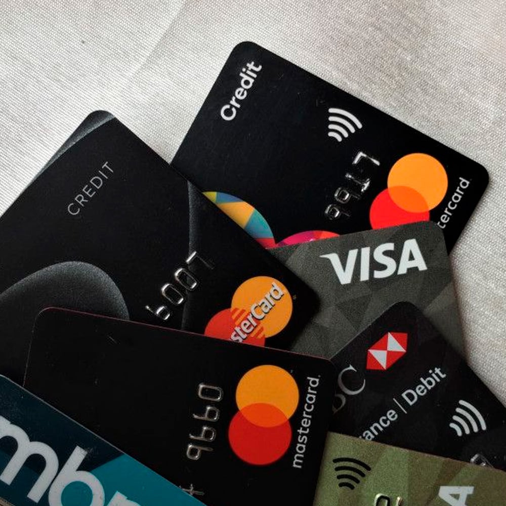 Several credit and debit cards, including Mastercard and Visa, are fanned out on a white surface, showing card logos and partial numbers.
