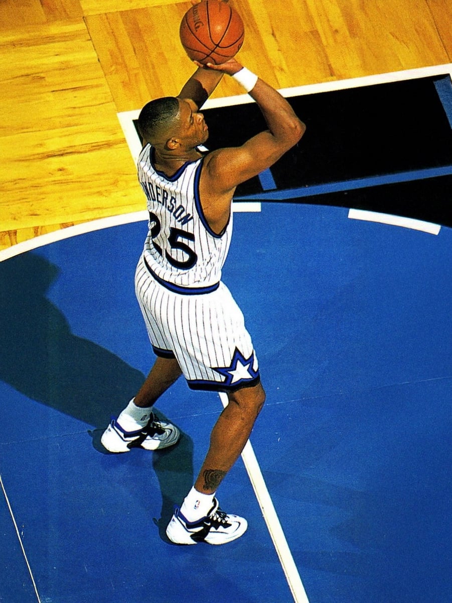 A basketball player in a white pinstripe jersey with number 25 prepares to shoot on a blue court, viewed from above. The court features a black key and wooden floor outside the paint.