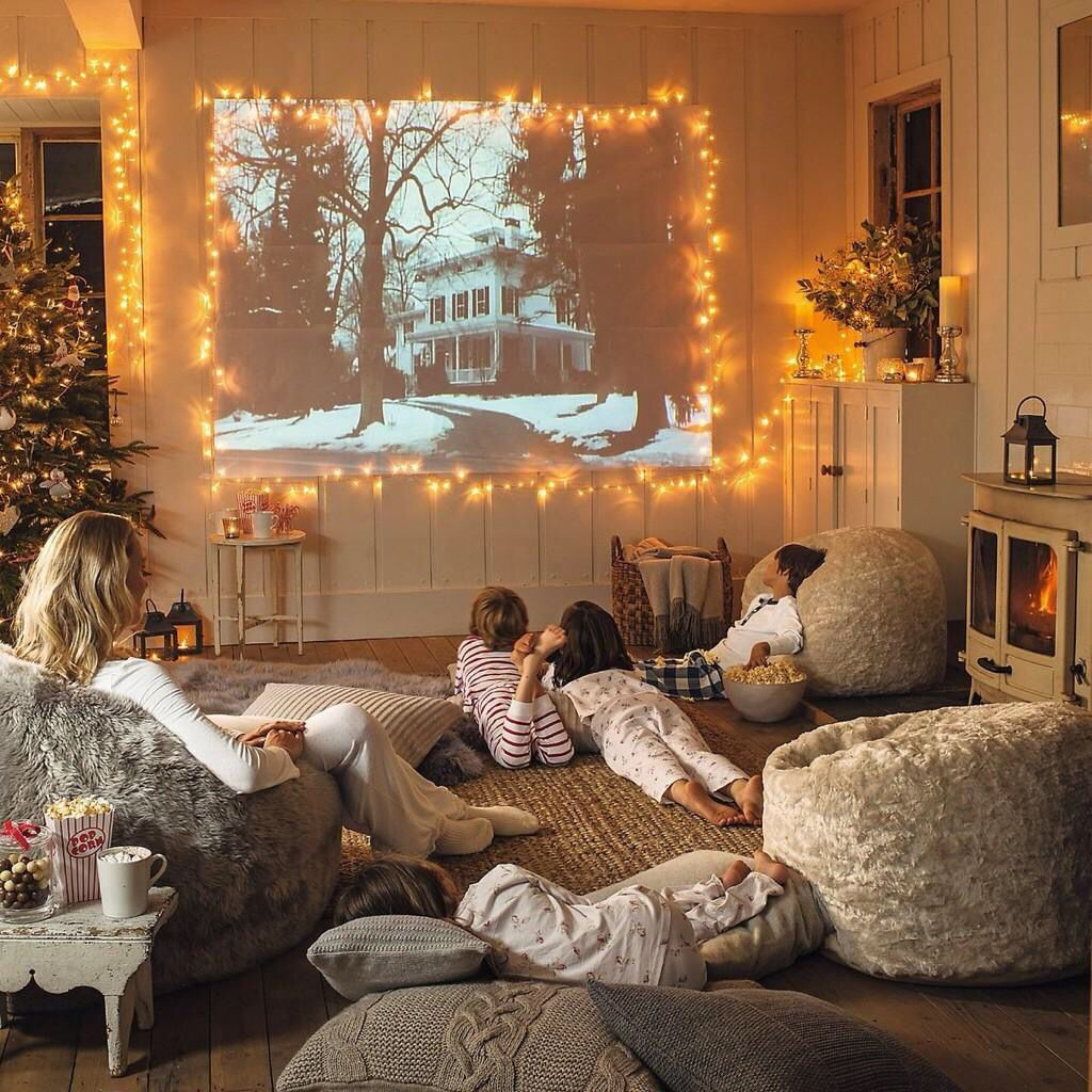 A cozy living room with four children and an adult watching a movie projected on the wall. The room is decorated with fairy lights, a Christmas tree, and comfy chairs, creating a warm, festive atmosphere.