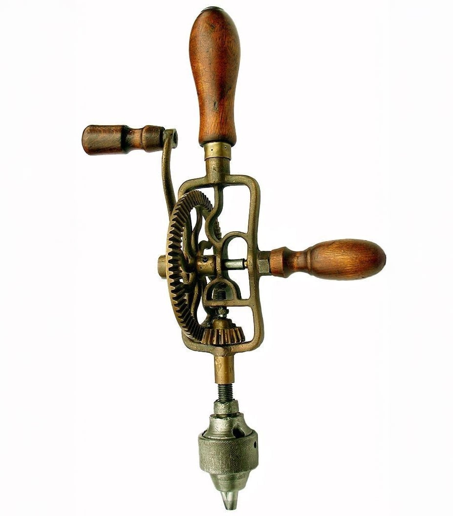A vintage hand drill with wooden handles and exposed metal gears, viewed from above, showing intricate mechanical details and a metal chuck at the bottom.