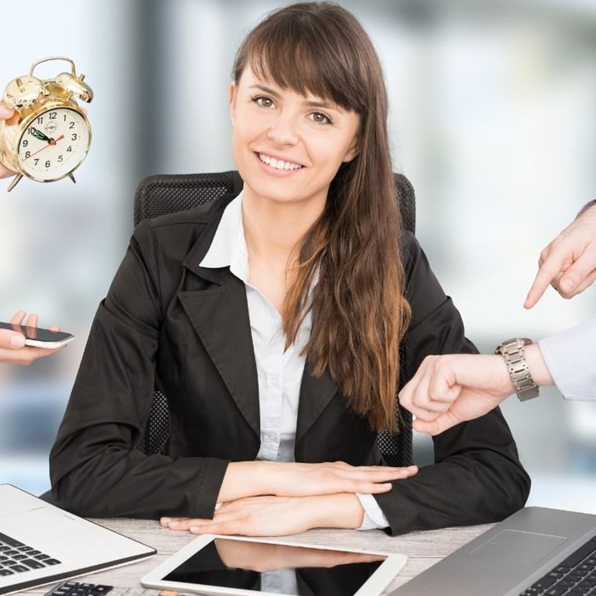A woman in business attire sits at a desk smiling, surrounded by hands holding a phone, a laptop, and pointing at a watch. An alarm clock is visible, suggesting a busy work environment and time pressure.