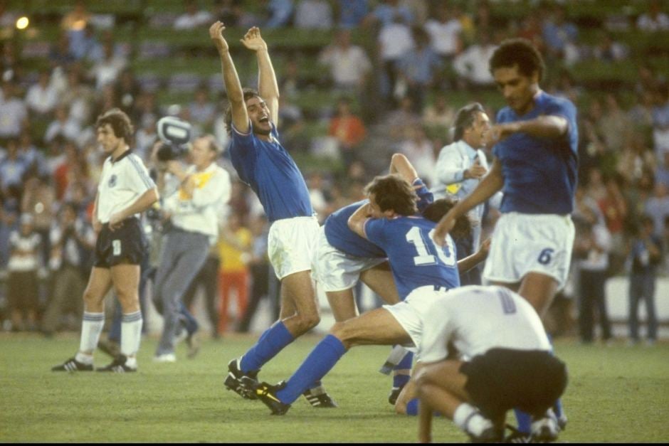 Italian soccer players in blue jerseys celebrate jubilantly on the field, while German players in white appear dejected after a match, with a crowd watching in the background.