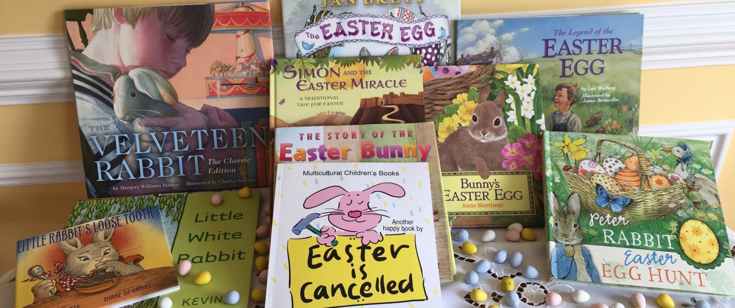 A collection of Easter and rabbit-themed children's books is displayed upright and scattered on a table with pastel candy eggs. Titles include "The Velveteen Rabbit," "Bunny's Easter Egg," and "Easter is Cancelled.