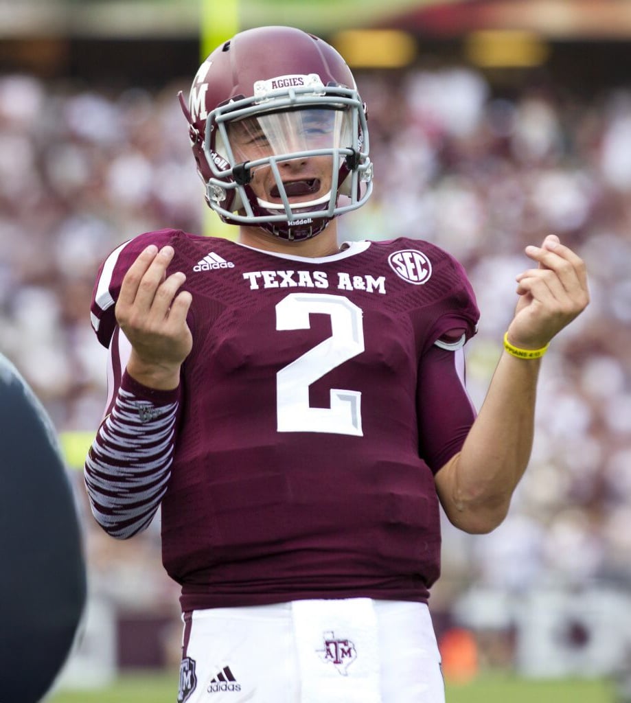 A Texas A&M football player wearing jersey number 2 gestures with both hands, appearing expressive during a game. He is in full uniform with a helmet, and the stadium crowd is visible in the blurred background.