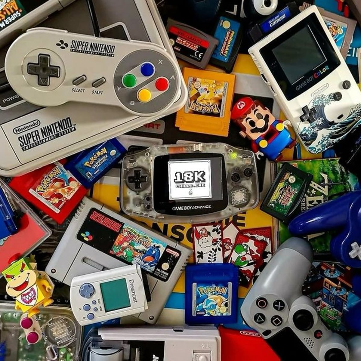 A variety of retro gaming consoles, controllers, and cartridges, including a Game Boy Advance, Super Nintendo controller, PlayStation controller, and several classic game cartridges, are scattered in a colorful pile.