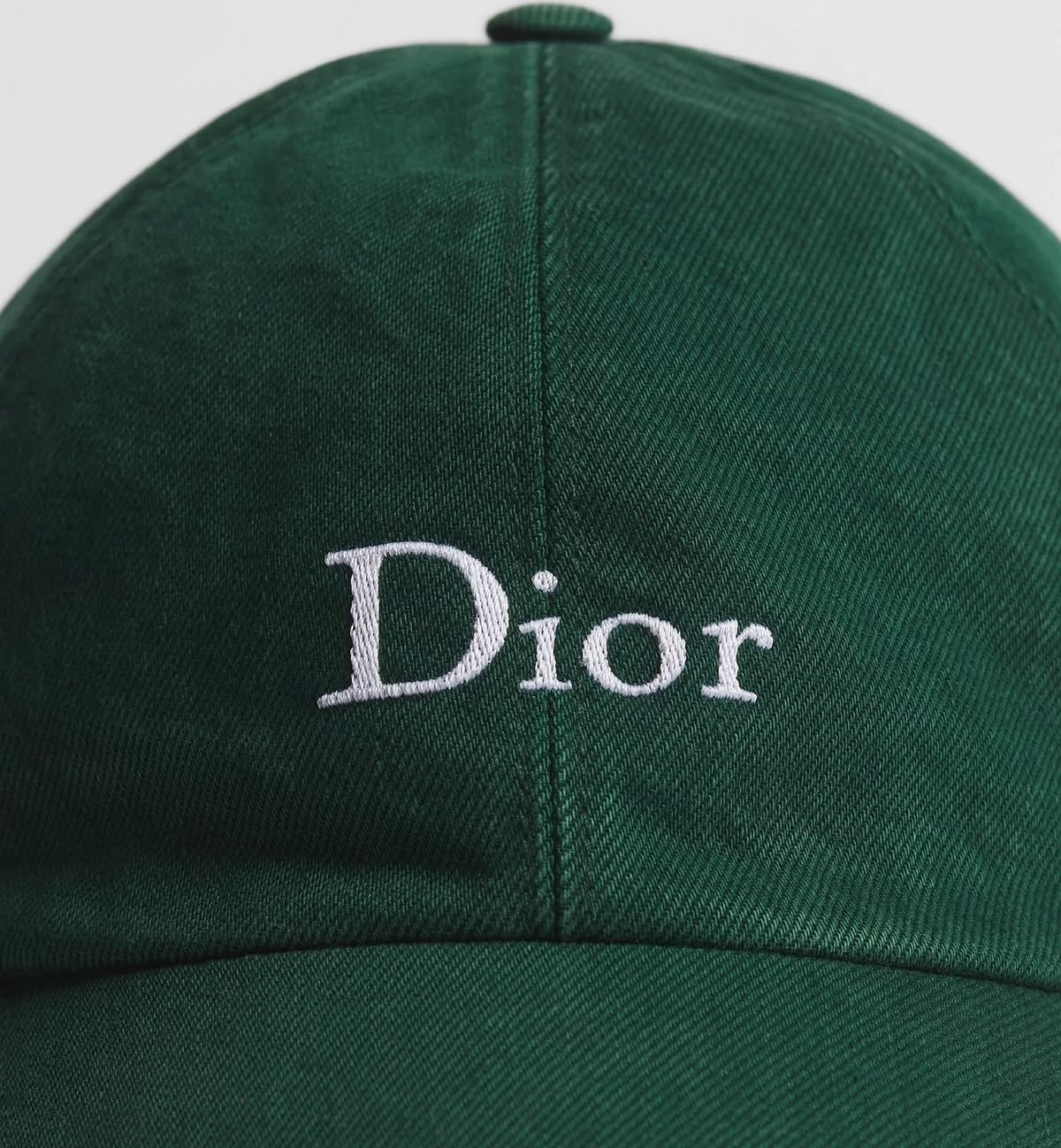 Close-up of a dark green baseball cap with the word "Dior" embroidered in white letters on the front.