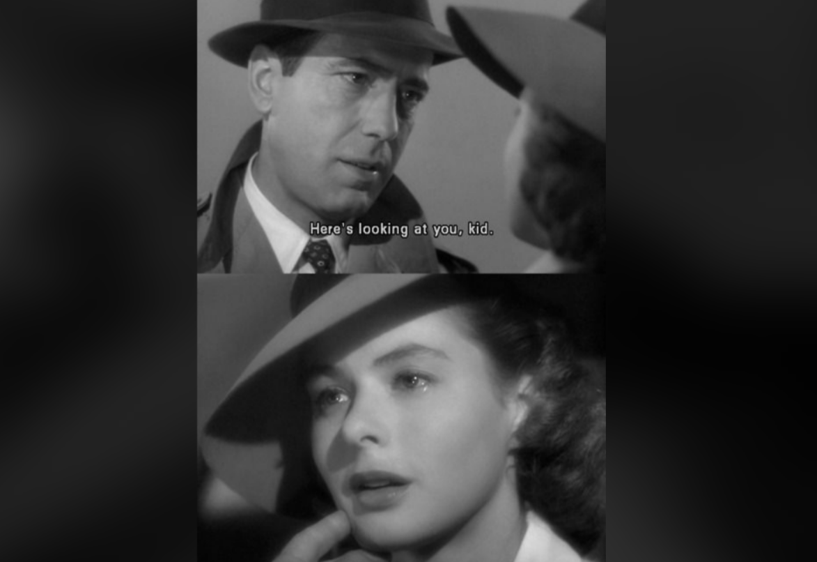 A black-and-white film scene shows a man in a trench coat and fedora speaking to a woman in a hat. Subtitles read, "Here's looking at you, kid." The woman looks emotional and teary-eyed.