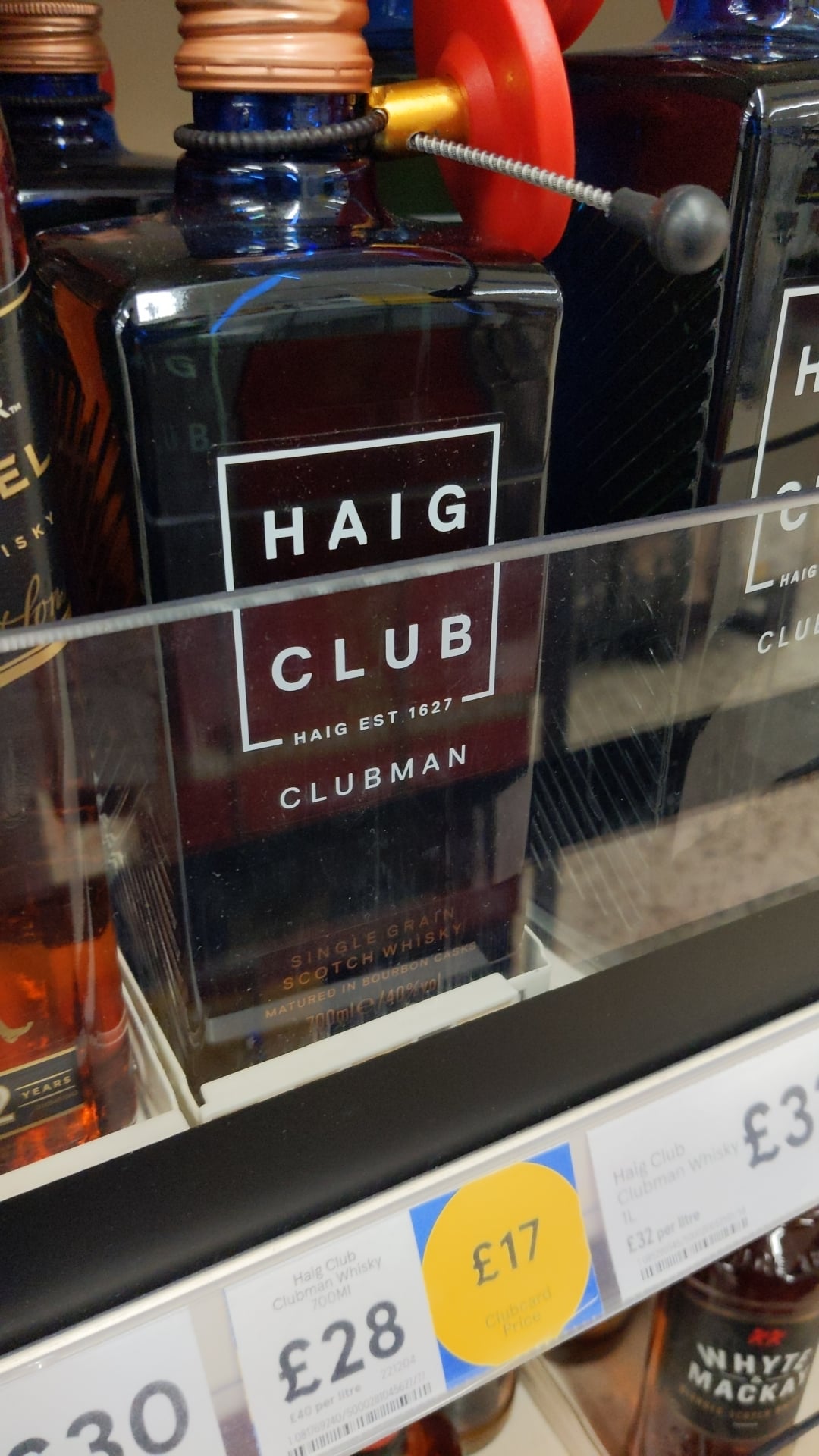 A bottle of Haig Club Clubman single grain Scotch whisky on a store shelf, priced at £17, with other bottles and price labels visible nearby.