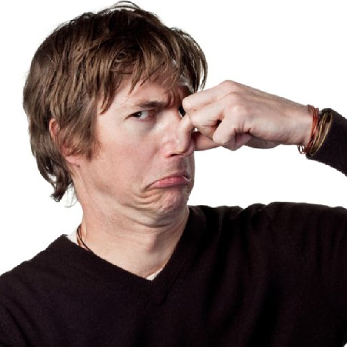 A man wearing a black sweater pinches his nose and makes a disgusted face, as if reacting to a bad smell. The background is plain white.