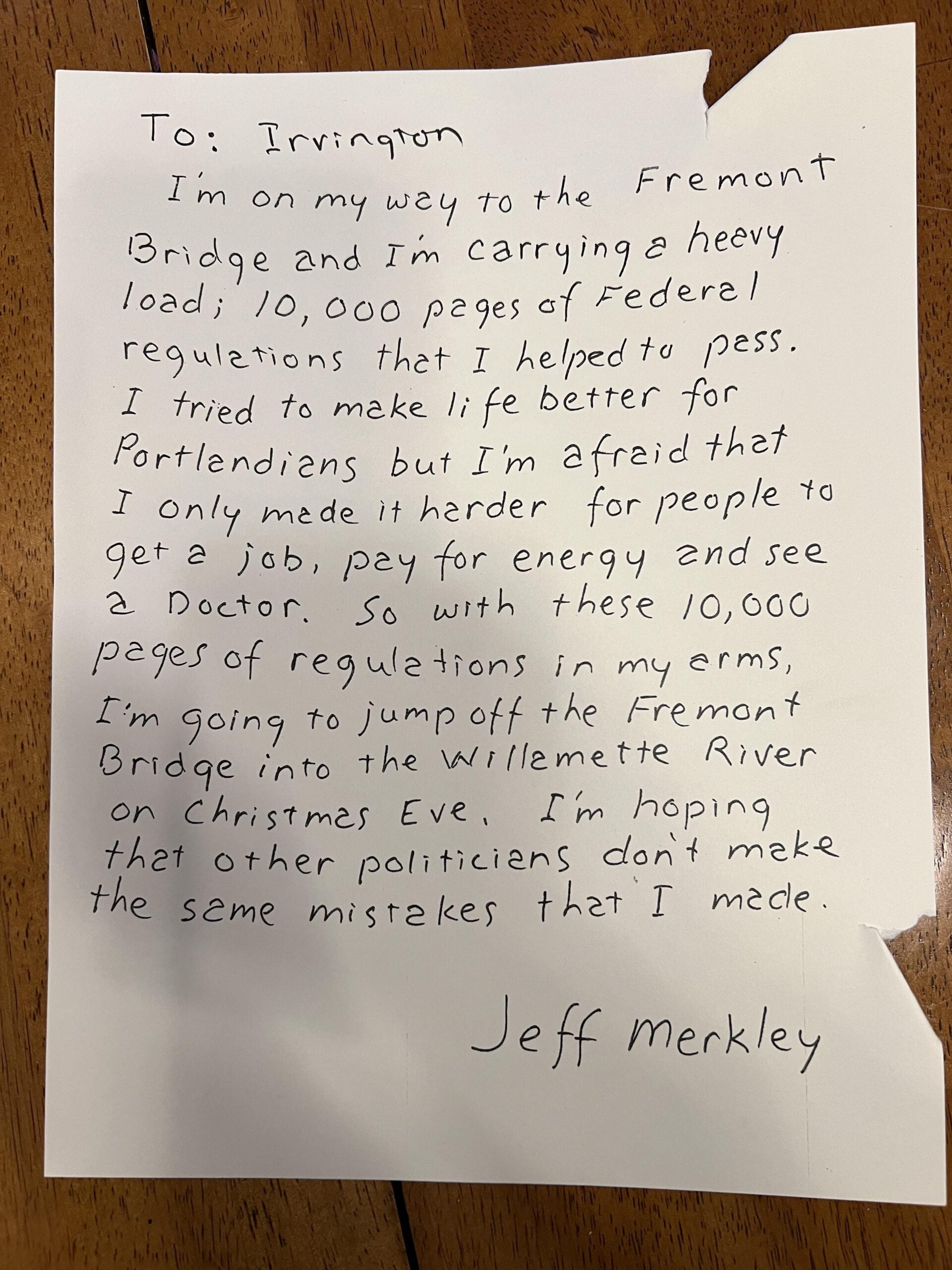 A handwritten letter on lined paper, addressed "To: Irvington,” describes carrying 10,000 pages of federal regulations and the writer’s regret, mentioning jumping off the Fremont Bridge. It’s signed "Jeff Merkley.