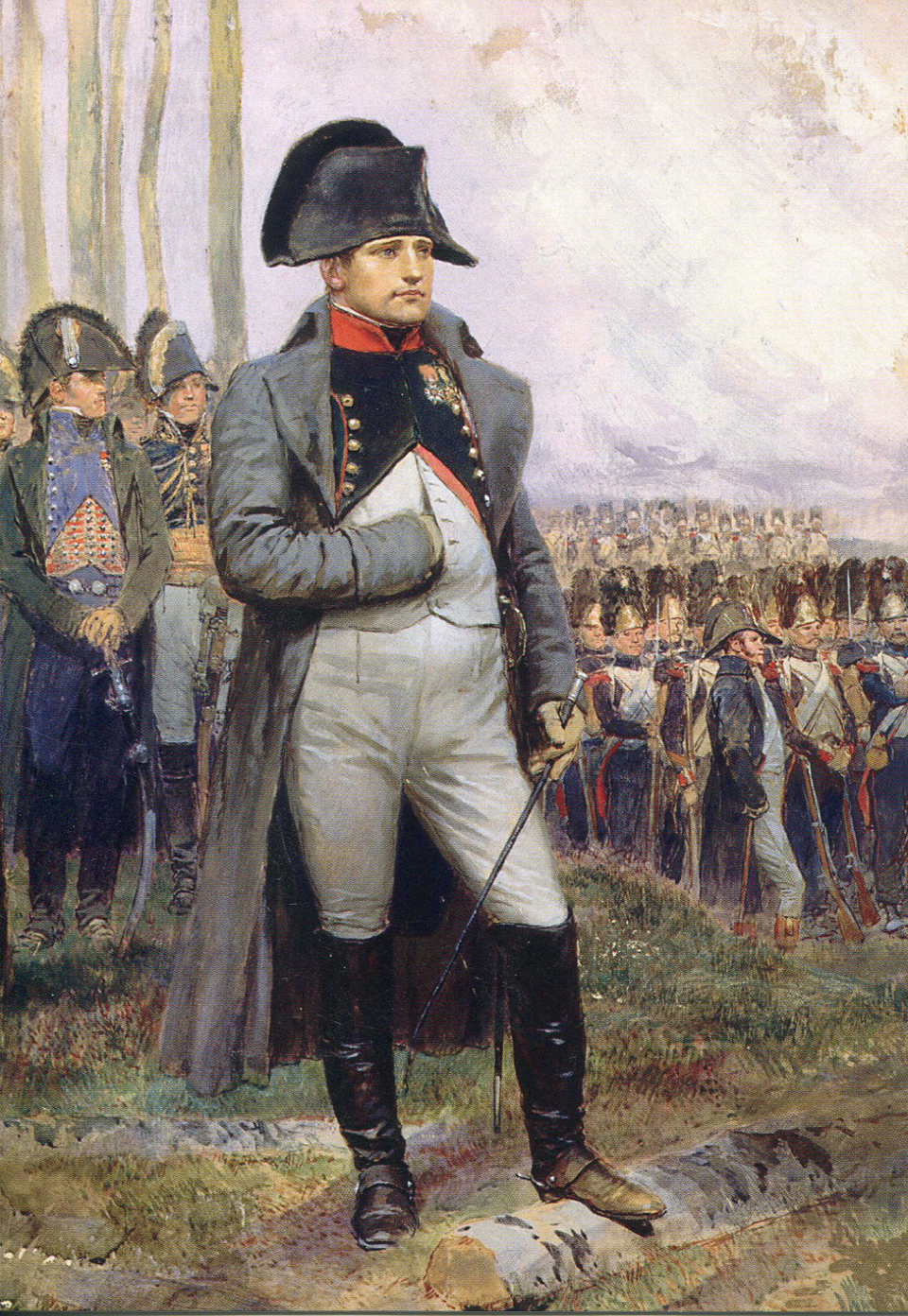 A man in a military uniform and bicorne hat stands with one hand inside his coat, in front of a group of soldiers lined up outdoors. Trees and a cloudy sky are in the background.