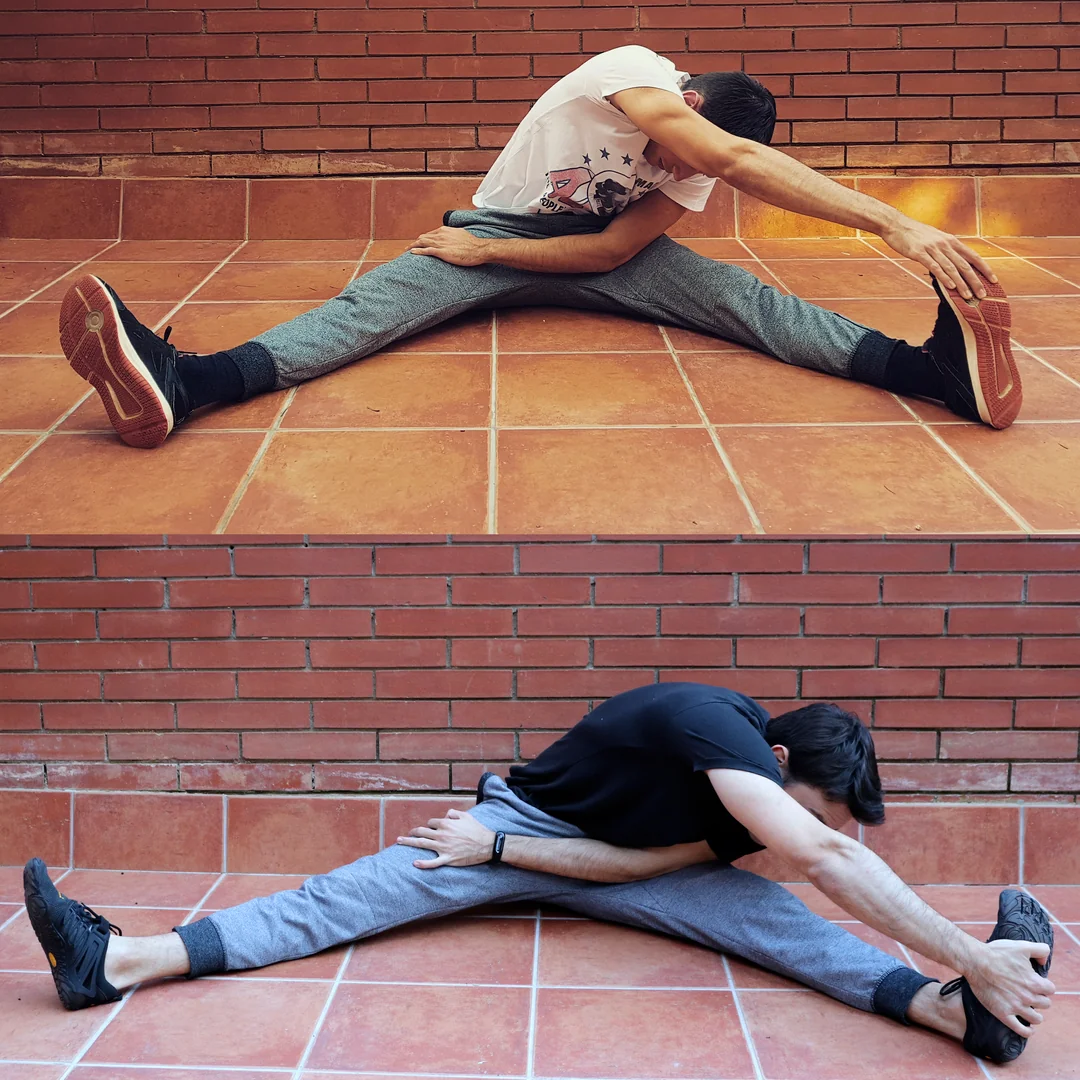 Two images show a person seated on a tiled floor, legs stretched wide apart, reaching one arm over to touch the opposite foot, performing side stretches against a brick wall background.