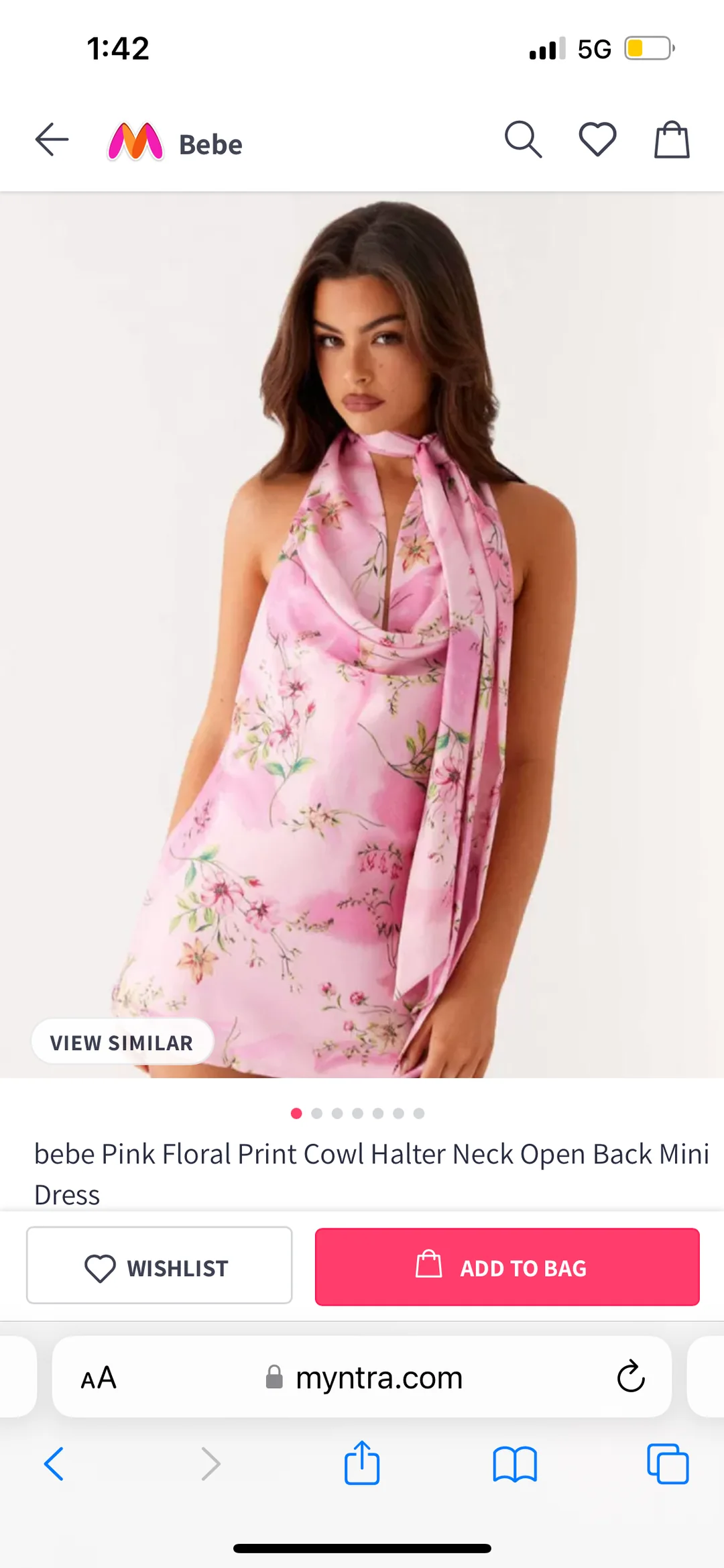 A woman models a pink floral print cowl halter neck mini dress with an open back. She stands against a plain white background, looking at the camera with a relaxed expression.