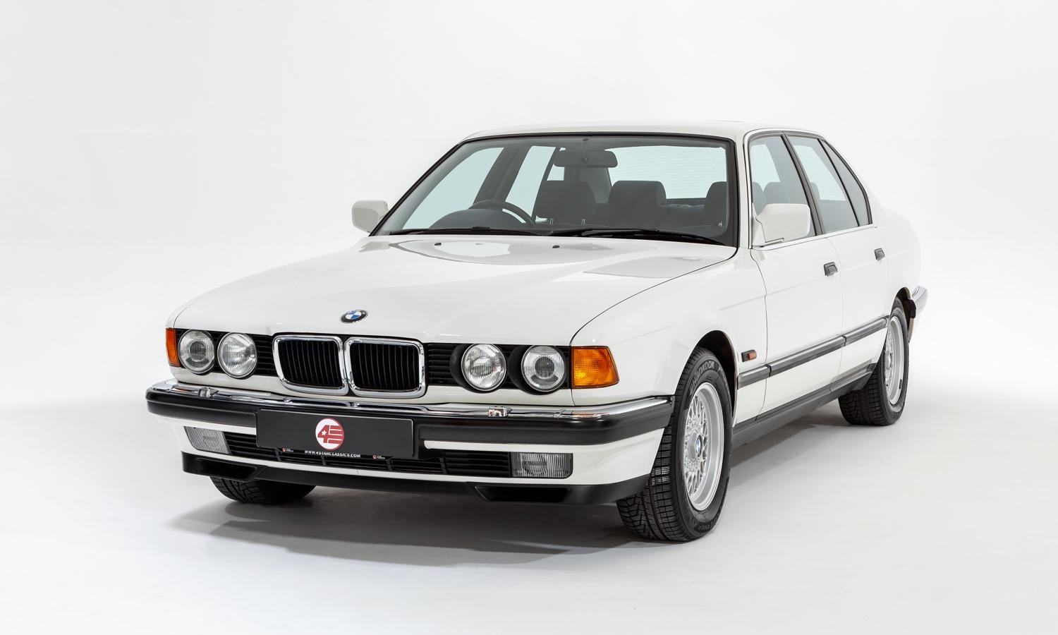 A classic white BMW sedan with four doors, circular headlights, and chrome BMW kidney grilles, parked on a plain white background.