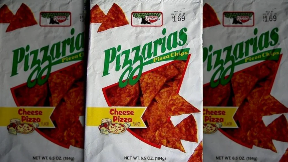 Bags of Pizzarias Pizza Chips, Cheese Pizza flavor, are displayed. The white bags feature green and red text, images of triangular chips, and a small pizza slice illustration. Each bag is 6.5 oz and priced at $1.69.
