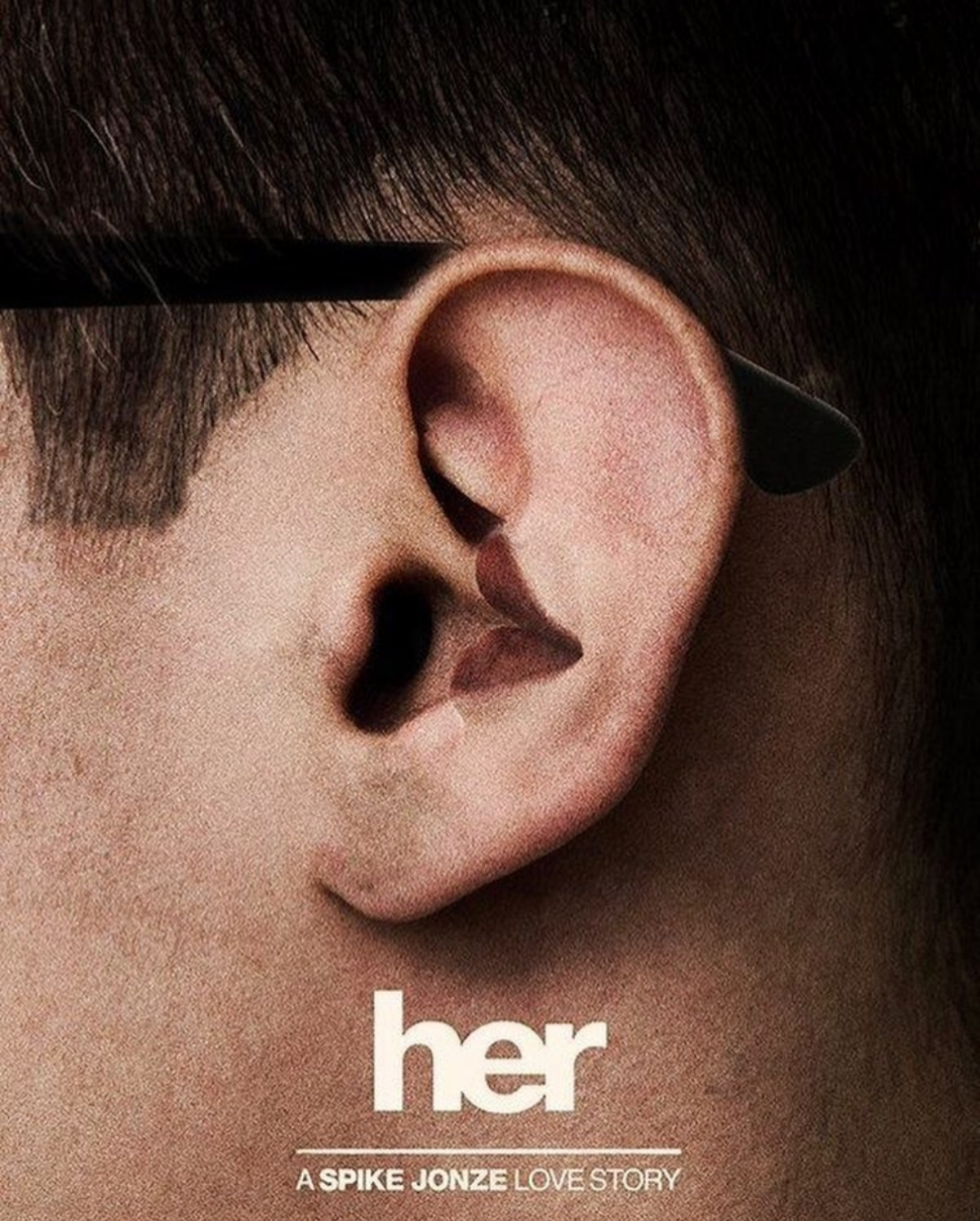 Close-up of a man's ear with an inner fold shaped like a heart. Below, text reads "her" and "A Spike Jonze Love Story" on a beige background.