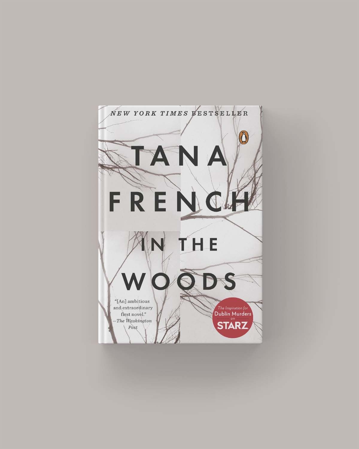 Book cover of "In the Woods" by Tana French, featuring large black text over a white background with thin tree branches. A red sticker notes its adaptation as a Starz TV series.