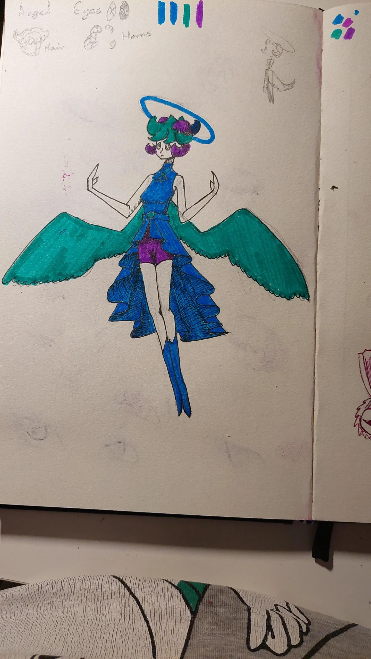 A colorful drawing of a character with teal wings, a blue dress, blue boots, purple shorts, pink hair, and a blue halo above their head, standing with arms raised and fingers bent, on a sketchbook page.