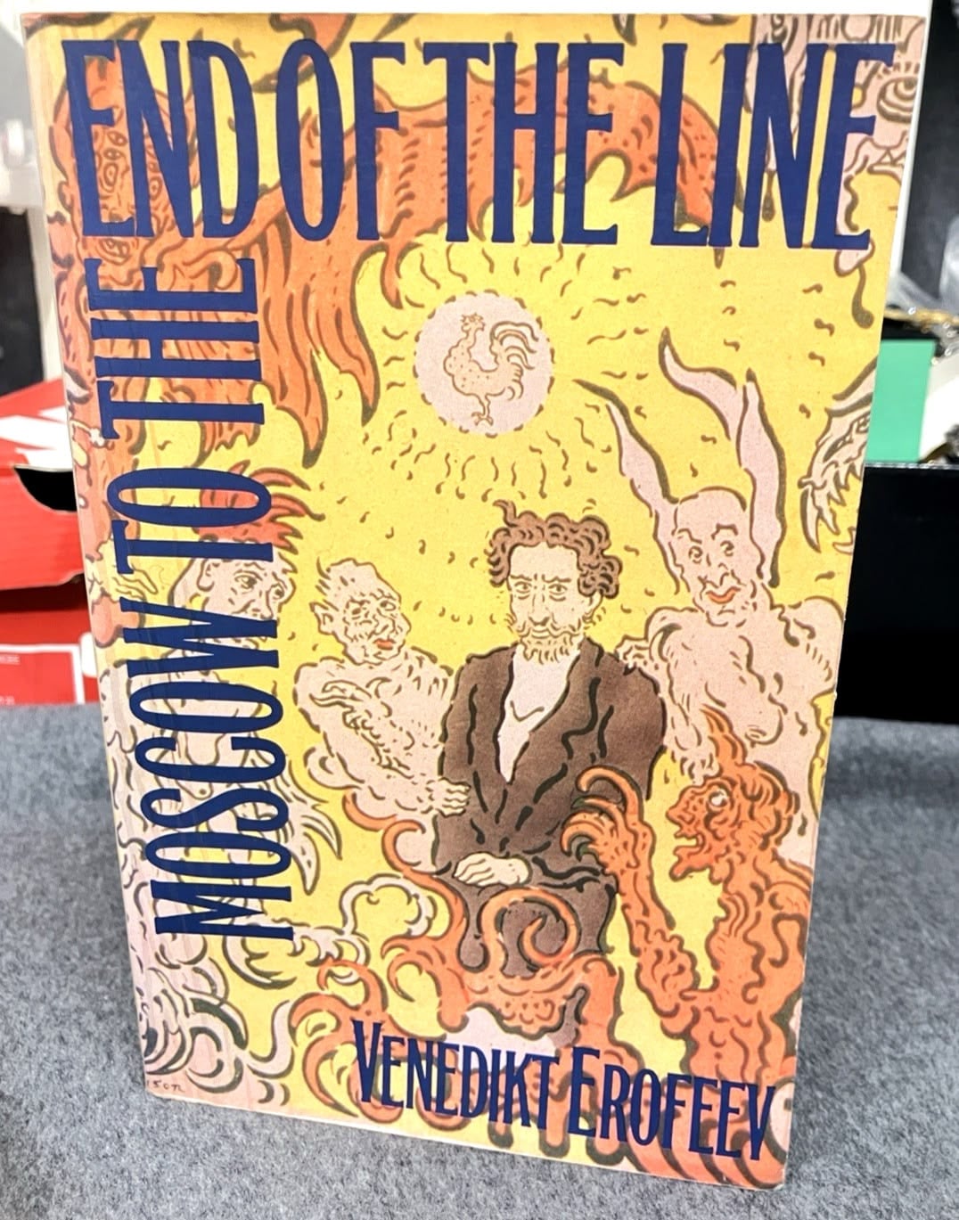 A book titled "End of the Line: Moscow to the" by Venedikt Erofeev features an abstract, surreal cover with distorted human figures, swirling patterns, and bright yellow, orange, and purple tones.