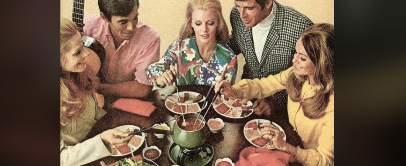 Five people sit around a table, smiling and dipping food into a green fondue pot. Each person holds a fondue fork and has a plate of food in front of them. The scene has a retro, vintage feel.