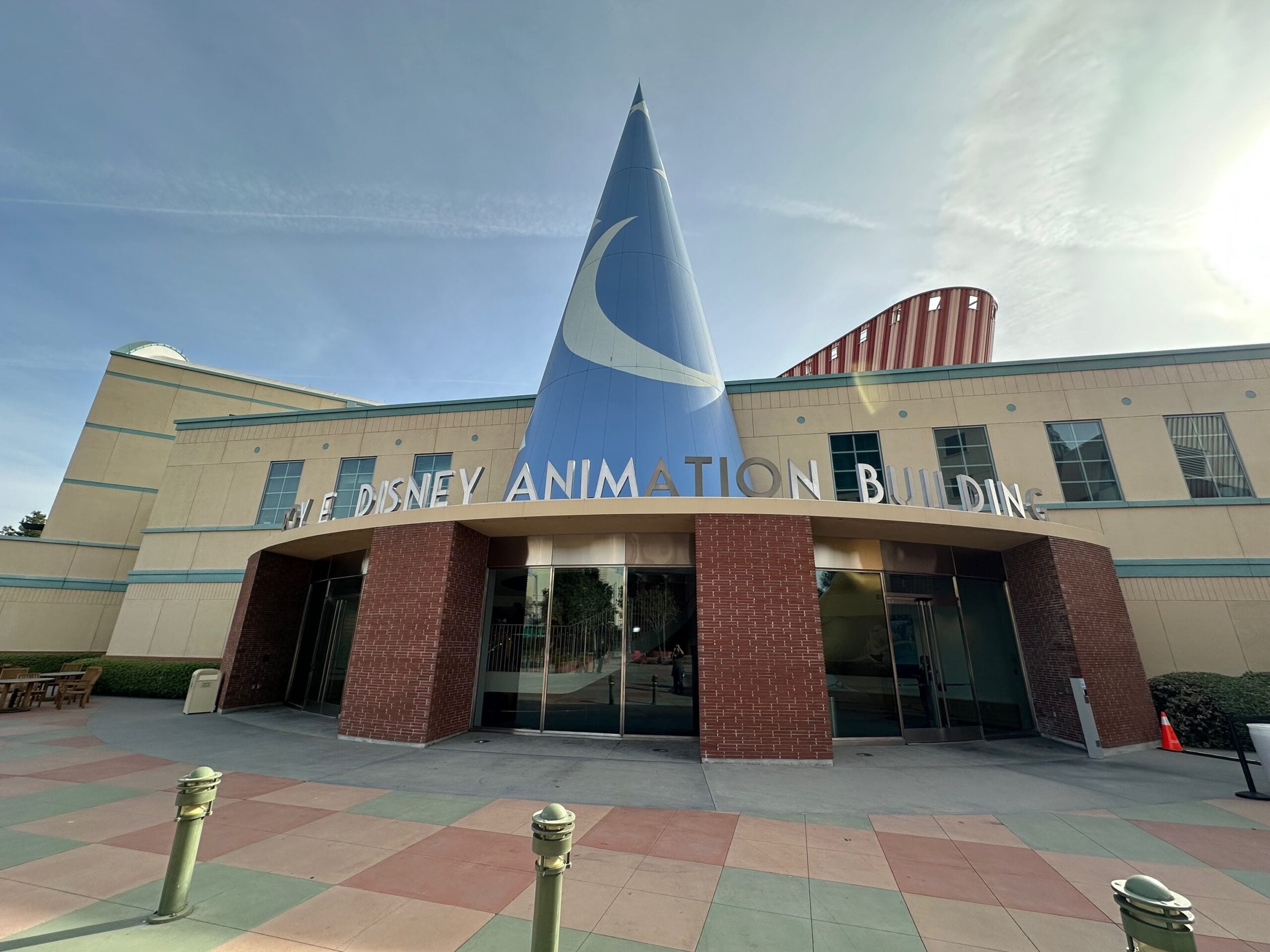 The front entrance of the Disney Animation Building features a large blue sorcerer’s hat with a crescent moon, glass doors, and "Disney Animation" lettering above the entrance.
