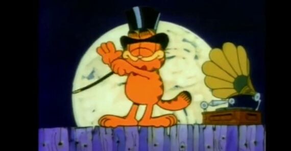 Garfield the cat wears a black top hat and holds a cane, standing on a wooden fence in front of a large full moon, with a vintage gramophone next to him.