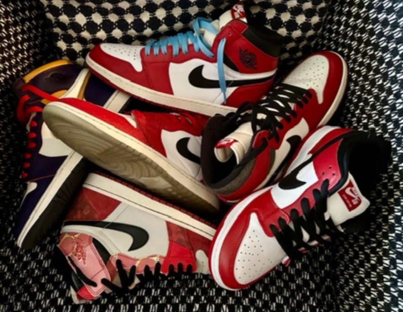 A pile of Nike Air Jordan sneakers with red, white, black, and hints of blue and yellow, arranged on a patterned black and white surface.