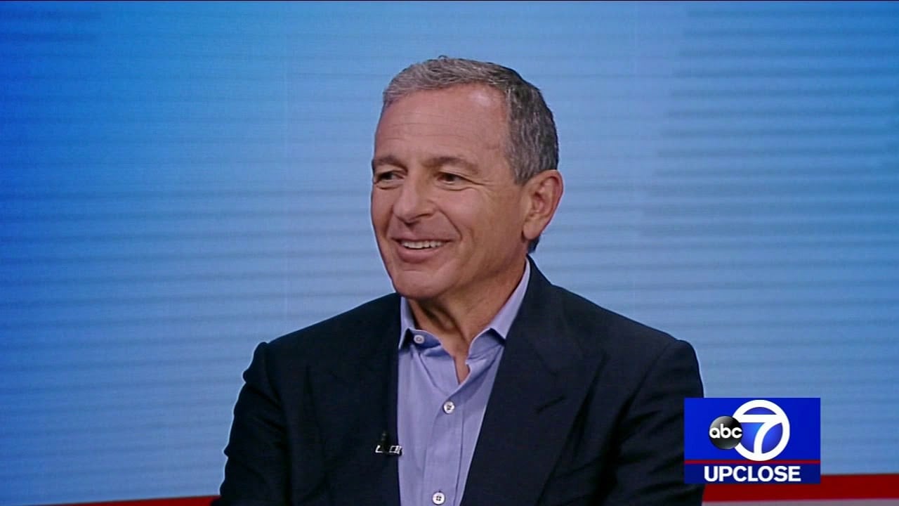 A smiling man in a suit sits for an interview on a TV program. The screen displays the ABC 7 UpClose logo in the bottom right corner. The background is light blue with subtle horizontal lines.