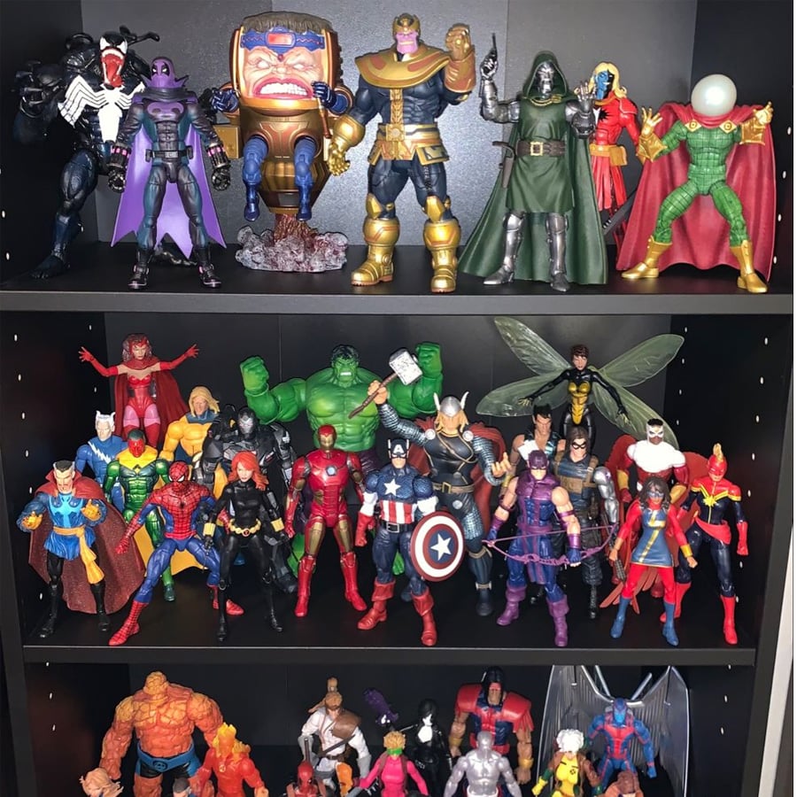 Three shelves display various Marvel action figures, including superheroes like Spider-Man, Captain America, Iron Man, Thor, Hulk, and villains such as Thanos and Doctor Doom, all posed in a collection.