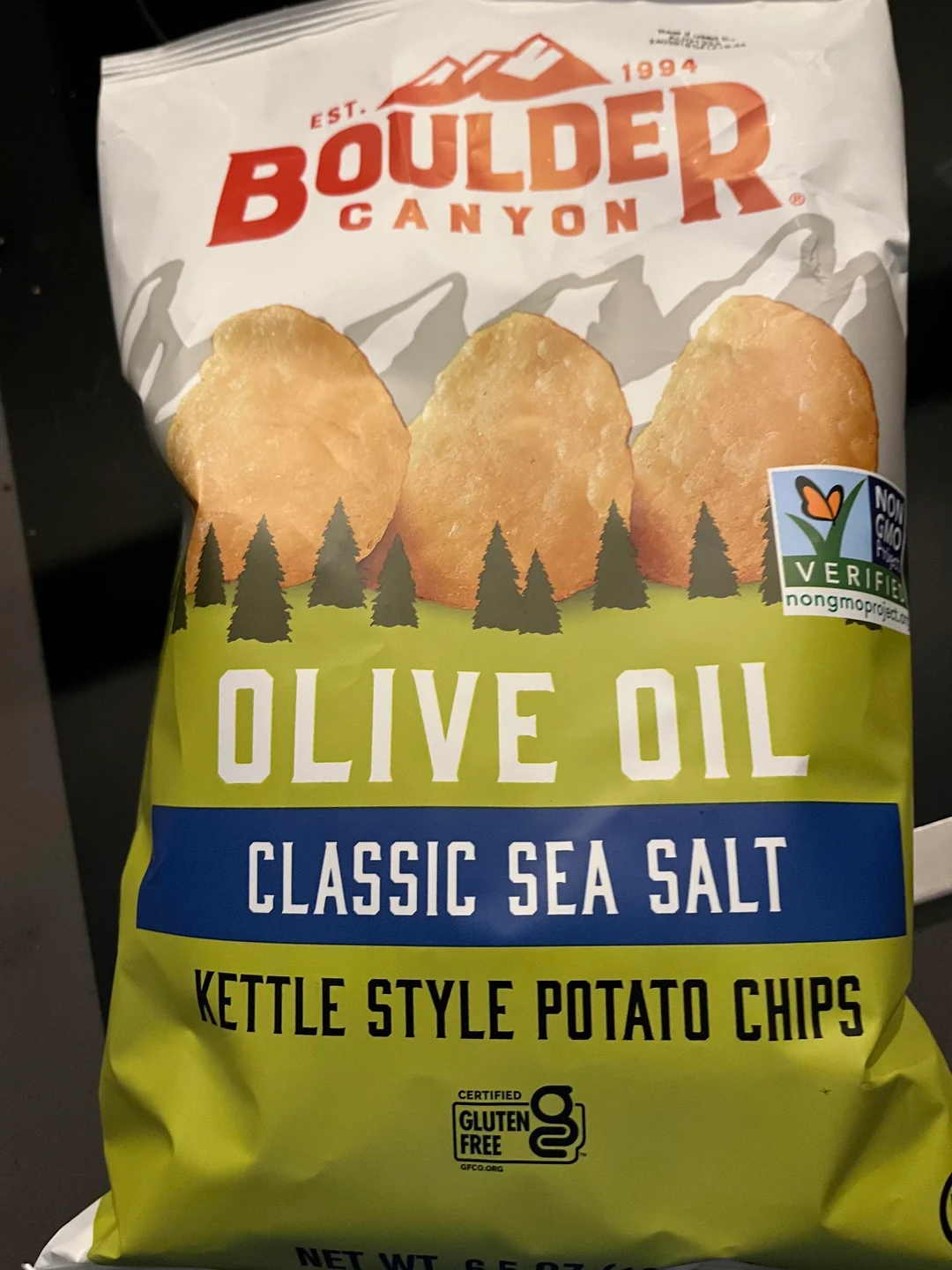 Bag of Boulder Canyon Olive Oil Classic Sea Salt Kettle Style Potato Chips, featuring images of potato chips above a forest design. Labels include "Non-GMO Project Verified" and "Certified Gluten Free.