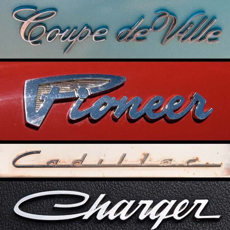 Four vintage car nameplates: "Coupe de Ville" in blue script, "Pioneer" in chrome on red, "Cadillac" in gold on cream, and "Charger" in chrome on black. All feature distinctive retro lettering styles.