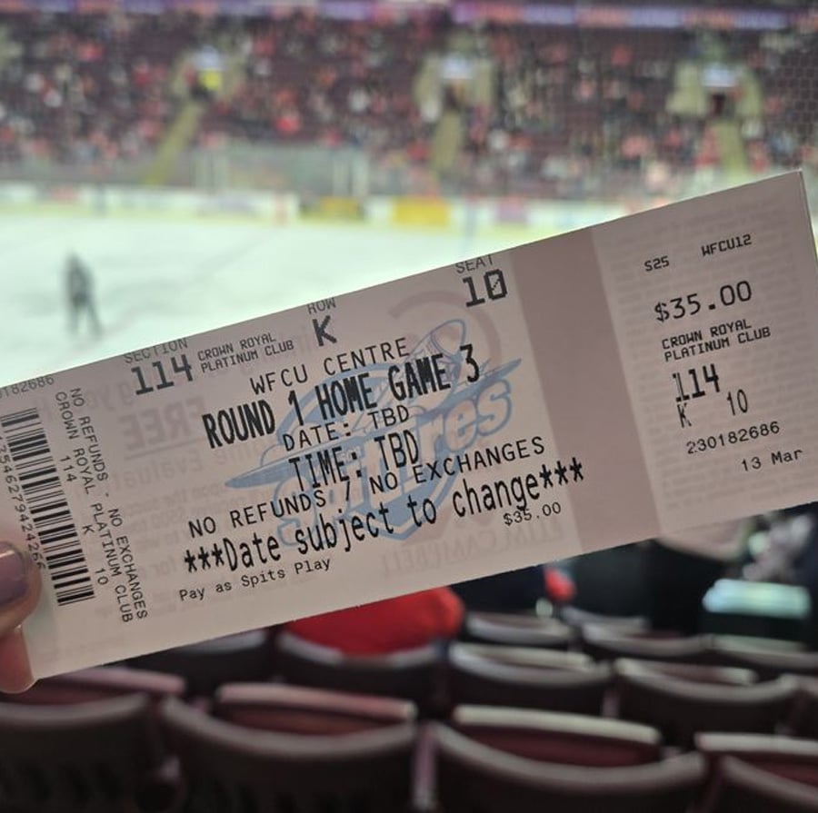 A hand holds a hockey game ticket inside an arena with ice and players visible in the blurred background. The ticket is for "Round 1 Home Game 3" at WFCU Centre, with date and time listed as TBD.