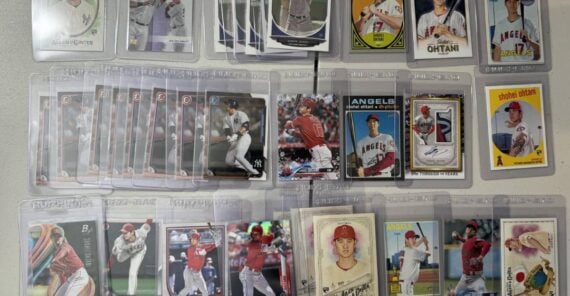 A collection of 27 baseball cards, mostly featuring Shohei Ohtani in various team uniforms, displayed in protective sleeves and arranged neatly on a white surface.