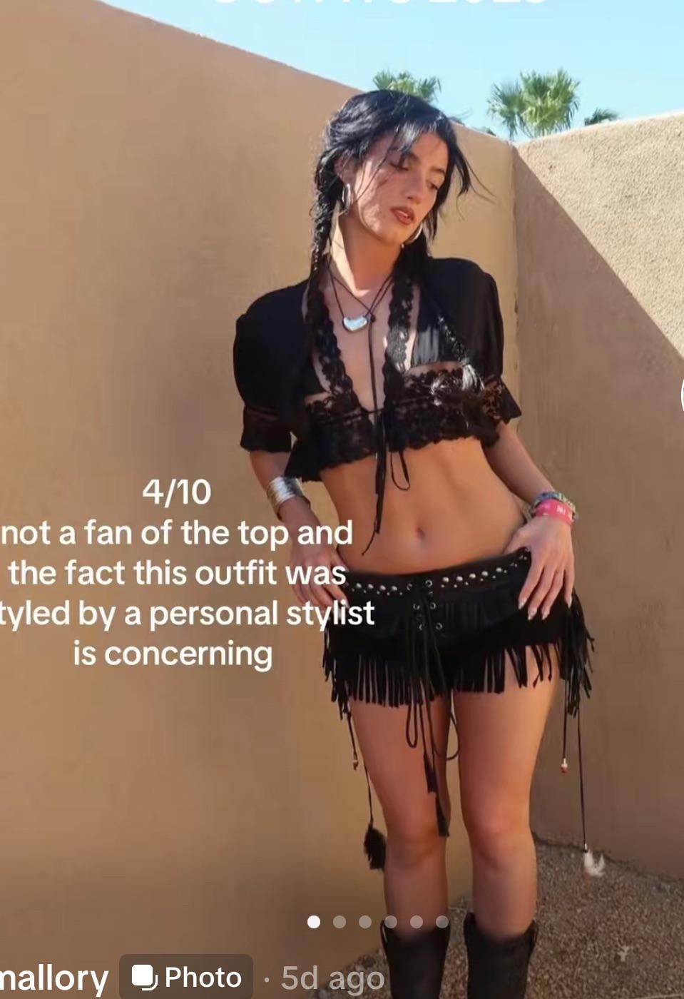 A woman stands outdoors in a black lace bralette, cropped jacket, and a black fringed mini skirt with studded belt. She wears layered jewelry and has two braids. Overlay text rates the outfit 4/10 and comments on the styling.
