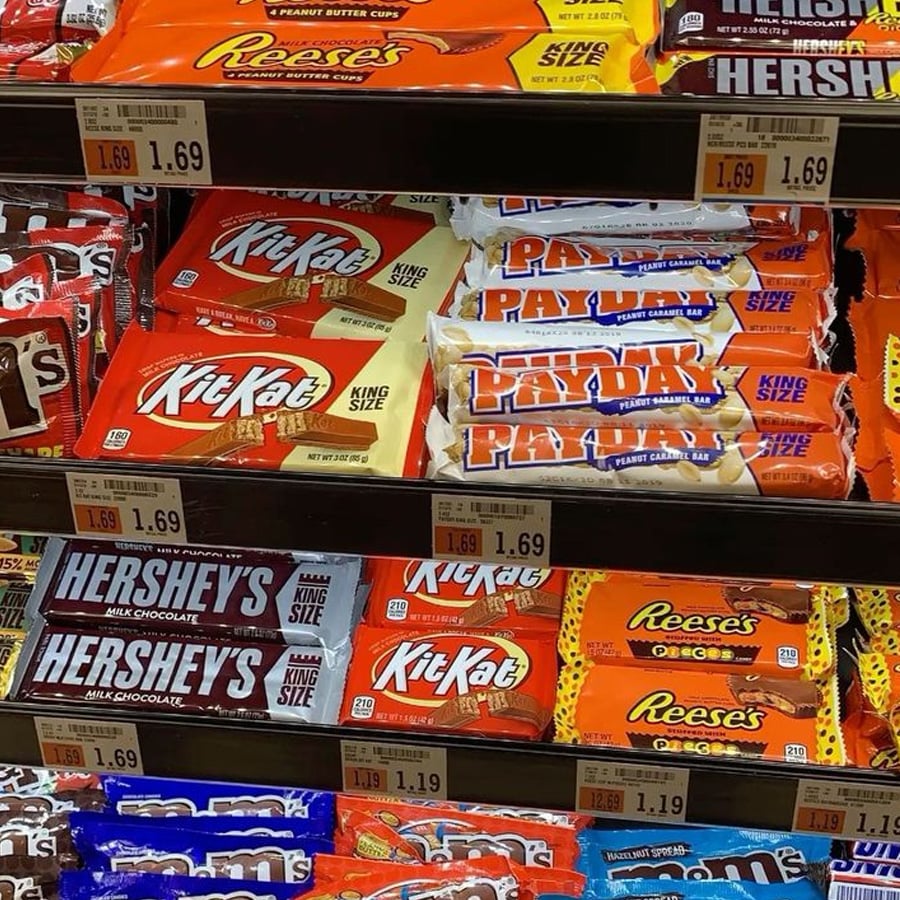 Shelves stocked with various king-size candy bars, including Reese's, Kit Kat, PayDay, Hershey's, and Reese's Pieces, each with price tags of $1.69.