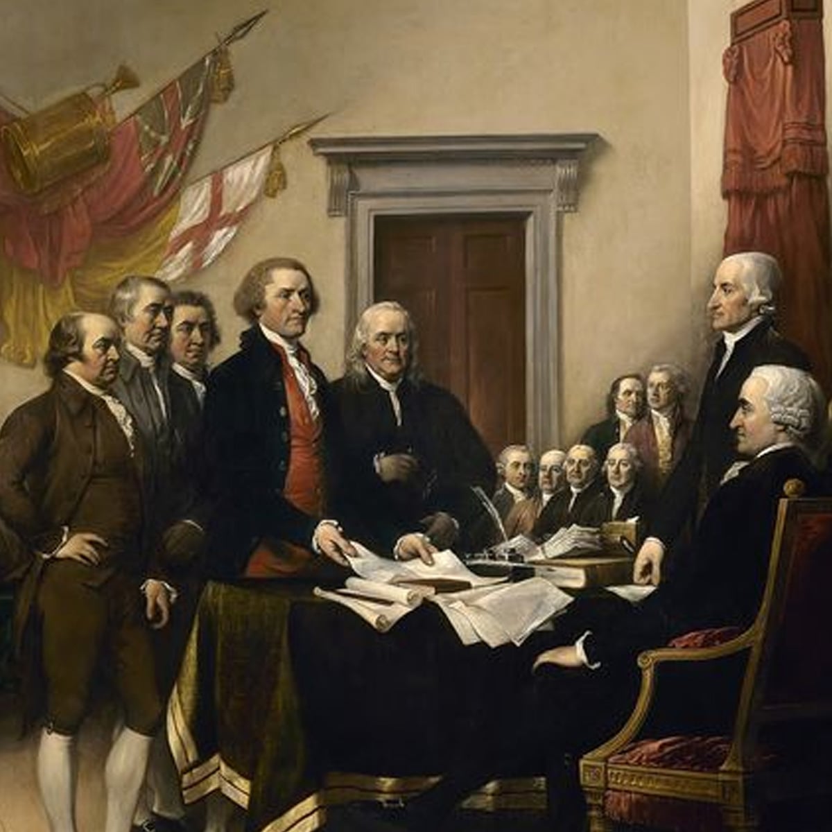 A group of men in 18th-century clothing gather around a table with documents in a formal room, depicting a historic moment of discussion and decision-making. A British flag hangs in the background.
