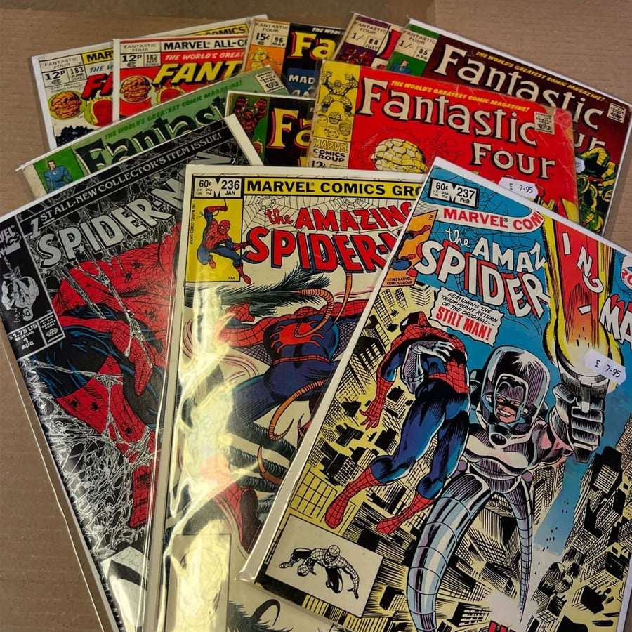A stack of vintage Marvel comic books, including issues of The Amazing Spider-Man and Fantastic Four, with colorful covers and price tags visible, arranged on a flat surface.