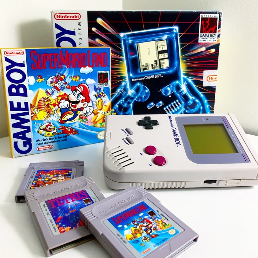 A classic Nintendo Game Boy with its original box, Super Mario Land game box, and three Game Boy cartridges—Super Mario Land, Tetris, and Spider-Man—displayed on a white surface.