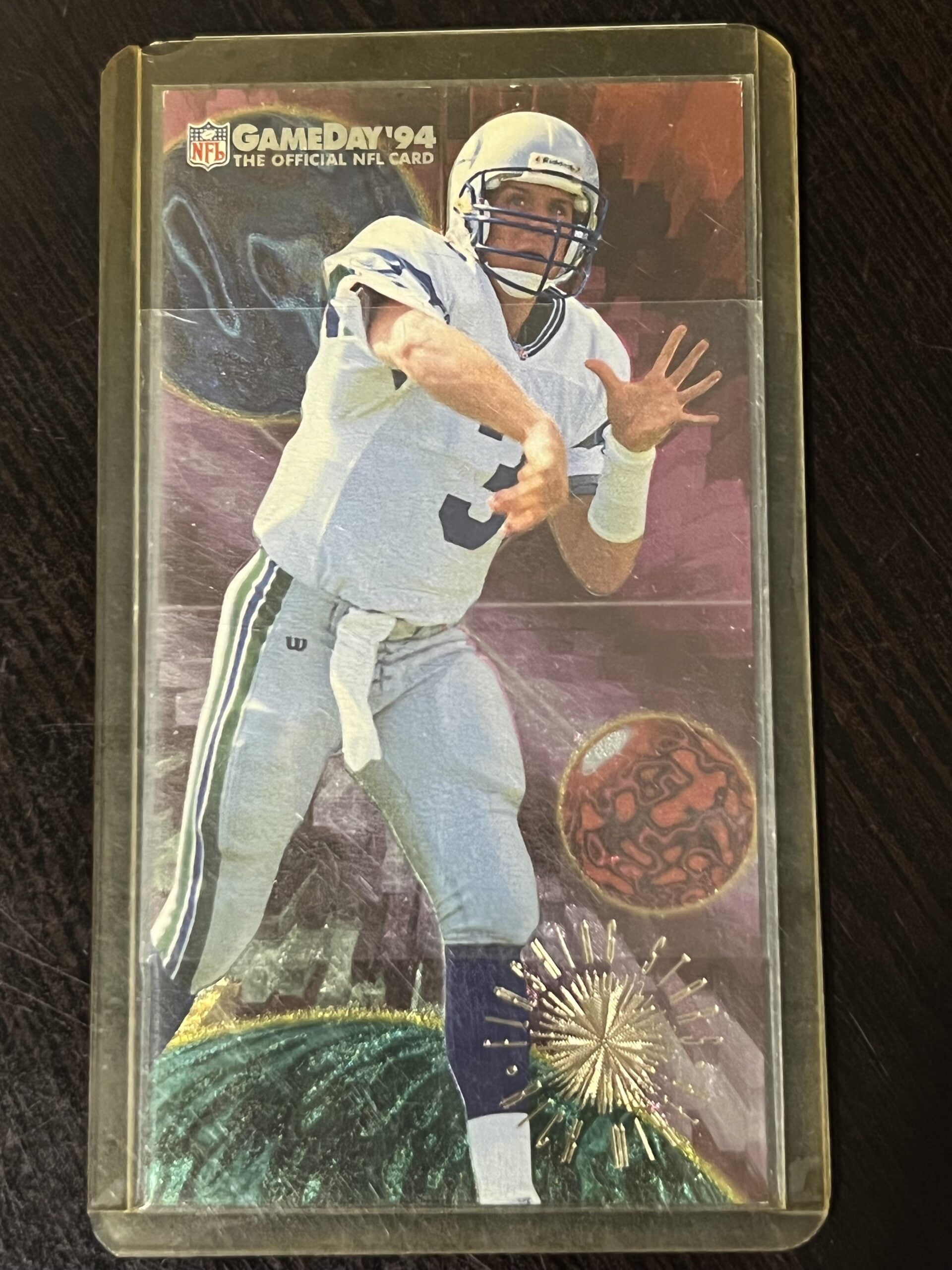 NFL GameDay '94 trading card featuring a football player in white uniform and helmet preparing to throw a pass, with a colorful, abstract background and fireworks design at the bottom. Card is in a plastic case.