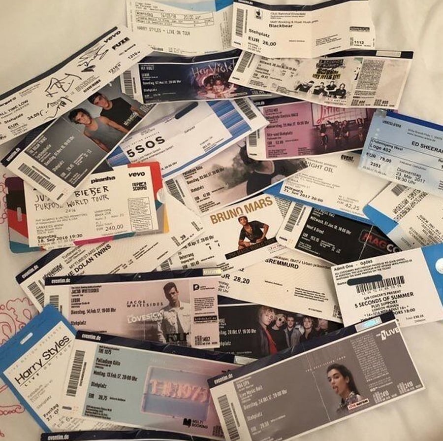 A collection of concert tickets scattered on a surface, featuring various artists and bands such as Harry Styles, Ed Sheeran, Bruno Mars, 5 Seconds of Summer, and others.