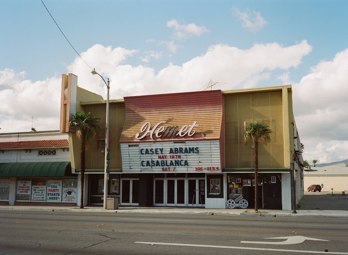 Street view of the Hemet theater with a marquee advertising “Casey Abrams May 18th” and “Casablanca Sat.” The building has retro signage, palm trees, and a cloudy sky in the background.