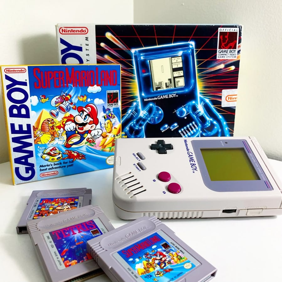 A classic Nintendo Game Boy system with its original box, the Super Mario Land game box, and four game cartridges: Super Mario Land, Tetris, Alleyway, and Baseball, displayed on a white surface.