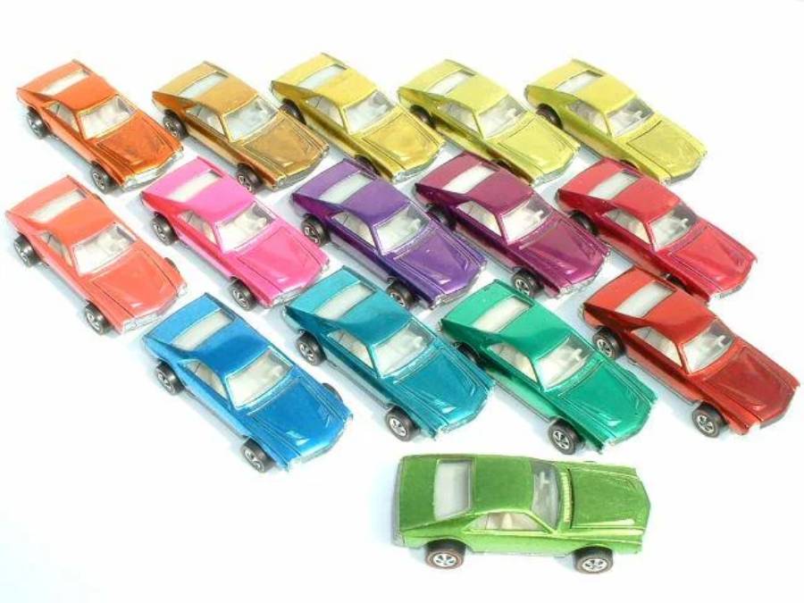 Fourteen toy cars in various colors are arranged in rows on a white background, with one green car positioned separately in front of the group.